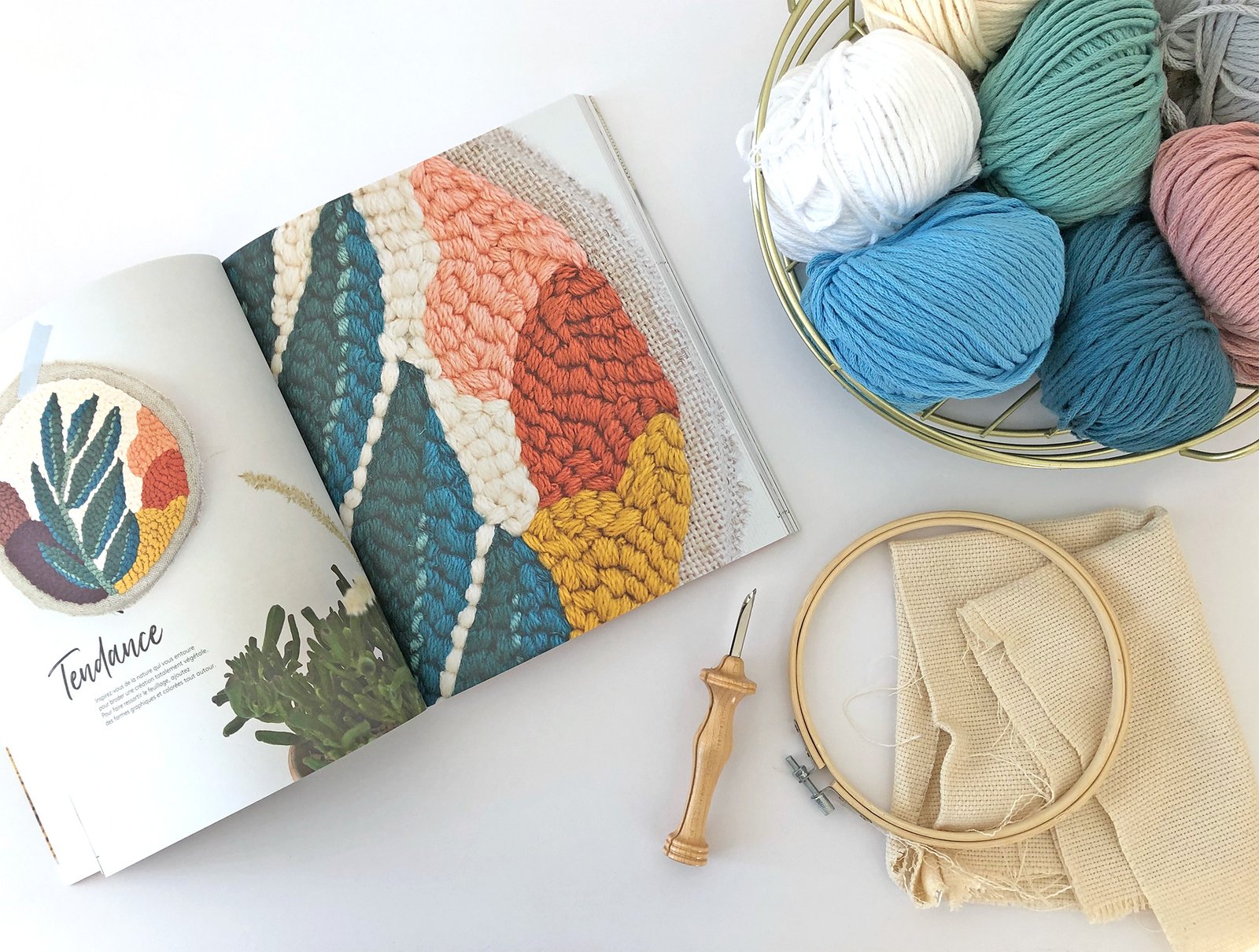 Une table avec un livre DIY et tout le matériel pour apprendre la broderie punch needle